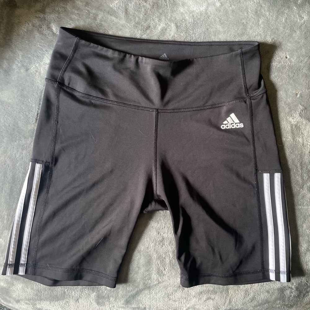 Large black Adidas biker shorts with white stripes.